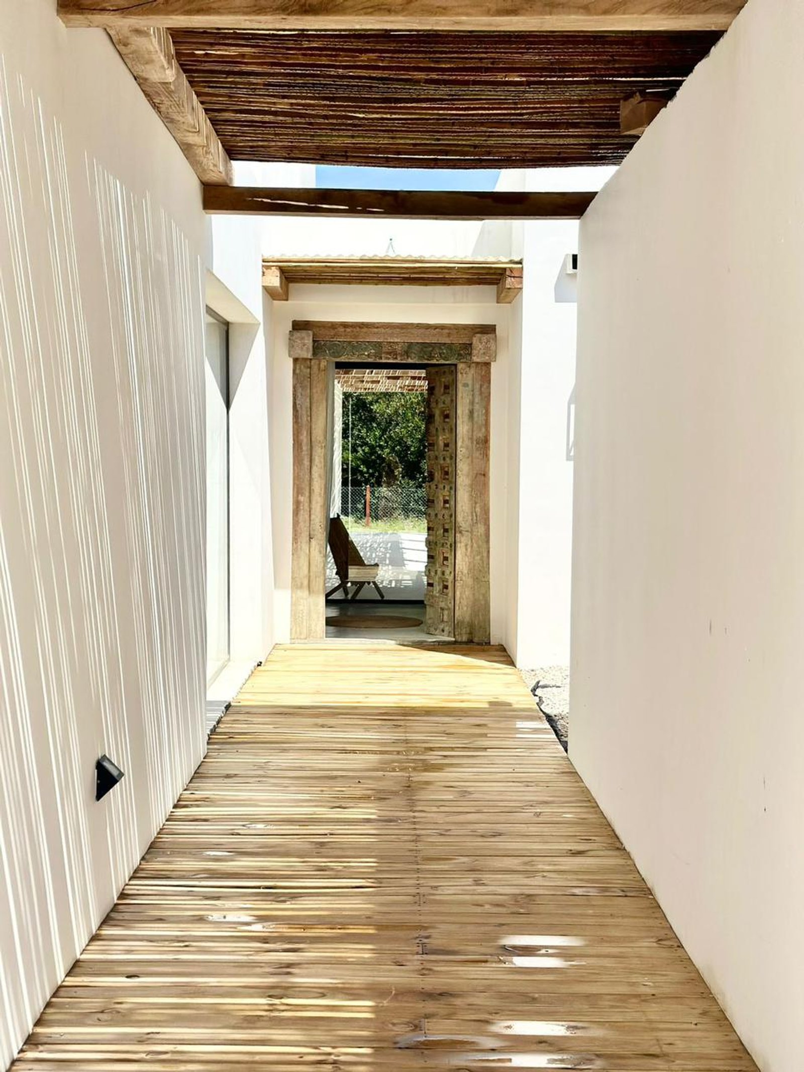 Pasillo con deck de madera hacia patio interior — proyecto CE, por arquitectura.JD, en Pinamar